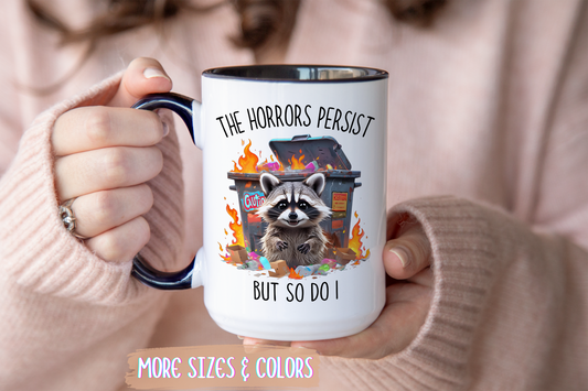 The Horrors Persist But So Do I Mug – Funny Raccoon Dumpster Fire Coffee Cup
